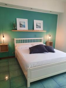 1 dormitorio con cama blanca y pared azul en MARE FUORI APARTMENT en Civitavecchia