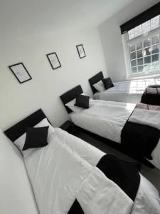 a bedroom with three beds with black and white sheets at Luxury Spacious 2-Bed House in Brentwood Essex in Brentwood