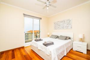 a white bedroom with a bed and a window at Bela Vista Valley in Calheta