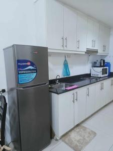 een keuken met een roestvrijstalen koelkast en witte kasten bij Ranj Staycation @ Sea Residences Pasay in Manilla