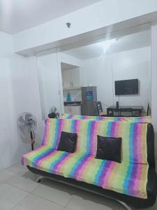 a bed with a colorful blanket in a room at Ranj Staycation @ Sea Residences Pasay in Manila