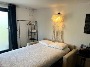 a bedroom with a bed and a lamp on the wall at Studio Strasbourg avec jardin in Strasbourg