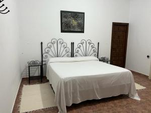 1 Schlafzimmer mit einem weißen Bett und 2 Tischen in der Unterkunft VFT Las Piedrecitas in Hornachuelos