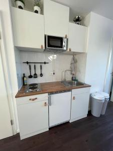 eine weiße Küche mit einer Spüle und einer Mikrowelle in der Unterkunft Gemütliche Dachgeschosswohnung in Mönchengladbach in Mönchengladbach