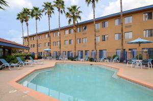 a swimming pool in front of a hotel with palm trees at Days Hotel by Wyndham Mesa Near Phoenix in Mesa