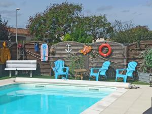a backyard with a pool with chairs and a fence with a mural at Philippe et Éliane in Matha