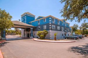 ein blaues Gebäude mit einem Parkplatz davor in der Unterkunft Days Inn & Suites by Wyndham San Antonio North/Stone Oak in San Antonio