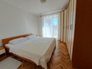 une chambre avec un lit blanc et une grande fenêtre dans l'établissement Apartments Maestral, à Malinska