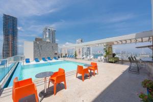 - une piscine au-dessus d'un bâtiment avec des chaises orange et une table dans l'établissement Hampton by Hilton Cartagena, à Carthagène des Indes