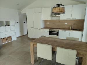 cocina con mesa de madera y armarios blancos en Gaja & Sara Apartments en Kozina