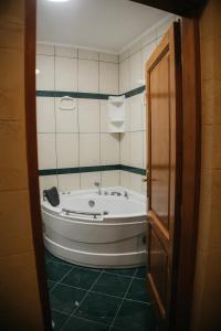 uma banheira na casa de banho com azulejos verdes em Macao Apartmani em Vinkovci