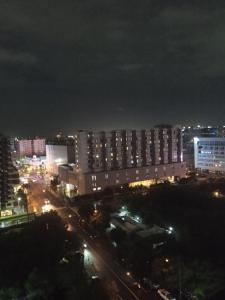 een stad 's nachts met gebouwen en straatverlichting bij Ranj Staycation @ Sea Residences Pasay in Manilla