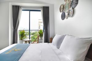 a bedroom with a large bed and a large window at Velar Hotel in Con Dao