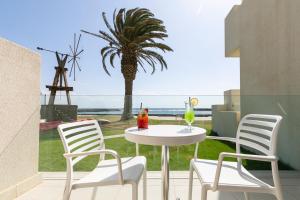 um pátio com uma mesa e cadeiras e uma palmeira em HD Beach Resort em Costa Teguise