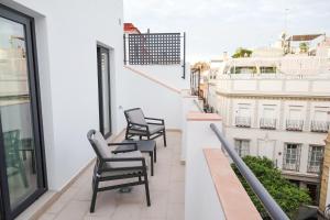 a balcony with chairs and a view of a building at Calma Suites in Seville