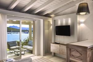 ein Wohnzimmer mit einem TV und Blick auf das Wasser in der Unterkunft 7Pines Resort Sardinia - A Destination By Hyatt in Baja Sardinia