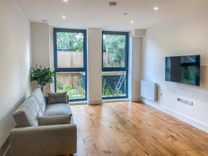 a living room with a couch and a tv at Heathrow Airport Apartments by Elegance Living in Hounslow