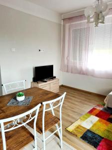 a living room with a wooden table and a television at A Grund Apartman in Balatonszabadi