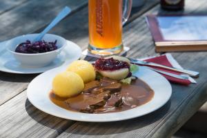 a plate of food on a wooden table with a drink at Brauereigasthof Rothenbach in Aufseß