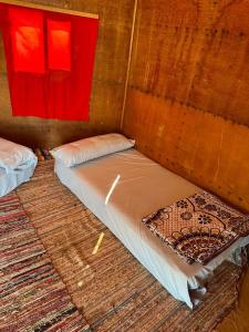 Cama en habitación de madera con ventana roja en Abo Hamada Azure Camp en Nuweiba