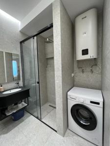 een badkamer met een wasmachine en een wastafel bij Lindi's Apartment 8/1 in Tirana