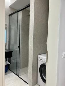een glazen douche in een badkamer met een wasmachine bij Lindi's Apartment 8/1 in Tirana