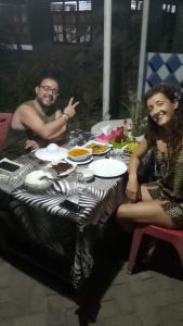 a man and woman sitting at a table with food at Naca Homestay in Manado