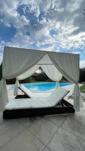 uma cama branca com um dossel ao lado de uma piscina em La Villa del Sol em Montélimar