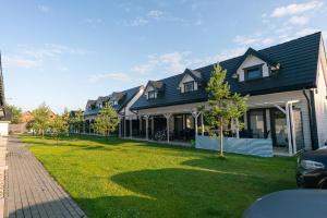 dom z zielonym trawnikiem przed nim w obiekcie Siedlisko Jantar Resort&Spa w mieście Jantar