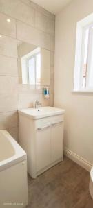 ein weißes Badezimmer mit einem Waschbecken und einem Spiegel in der Unterkunft Woodfield apartment in The Hyde