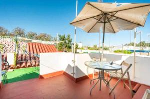 um pátio com um guarda-sol, uma mesa e cadeiras em Ikigai House em Sevilha