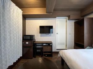1 dormitorio con 1 cama y escritorio con microondas en Cozy inn Oyama, en Tokio