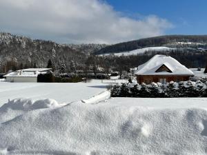 a snow covered house with a pile of snow at Domek na Słonecznym Pagórku in Baligród