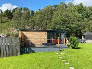 a small cabin in a yard with a fence at Balmaha Lodges and Apartments in Balmaha