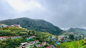 a village on a hill with houses and trees at Mountain View cottage in Ooty