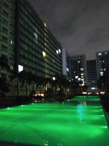 een zwembad van groene verlichting in een stad 's nachts bij Ranj Staycation @ Sea Residences Pasay in Manilla