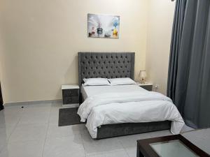 una camera con un grande letto con testiera grigia di Cozy Private Studio Apartment Near Airport a Abu Dhabi