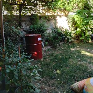 a red trash can sitting in the grass at Çatı katı, teraslı ve bahçeli, müstakil in Izmit