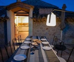 einem langen Tisch mit Stühlen und Tellern und einer Lampe in der Unterkunft Secluded house with amazing view and swimming pool in Buis-les-Baronnies
