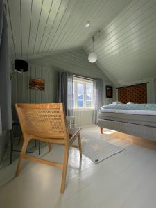 a bedroom with a bed and a chair in it at Eldhuset 1928 in Eidsbygda