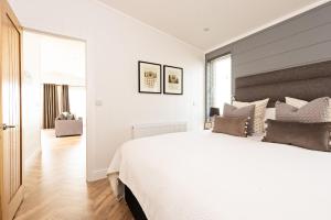 Un dormitorio blanco con una gran cama blanca y ventanas. en Shropshire Lodges - Romantic Luxury Hot Tub Breaks, en Bridgnorth