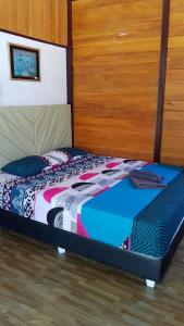 een bed met een kleurrijk dekbed in een kamer bij Naca Homestay in Manado