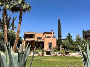 ein großes Haus mit Palmen davor in der Unterkunft Jolie villa Front de Golf in Marrakesch