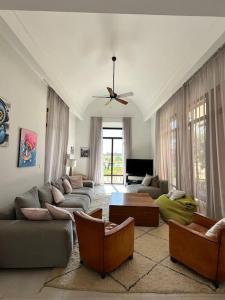 ein Wohnzimmer mit Sofas und einem Deckenventilator in der Unterkunft Jolie villa Front de Golf in Marrakesch