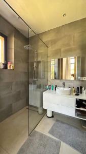 ein Bad mit einem Waschbecken und einer Glasdusche in der Unterkunft Jolie villa Front de Golf in Marrakesch