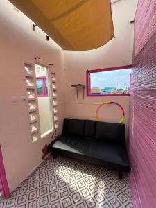 Sentool的住宿－Et Malio Stay & Travel，一间设有黑色沙发的粉红色墙壁客房