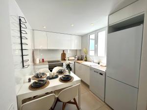 cocina con armarios blancos, mesa y sillas en Luxury Apartment Valencia Center en Valencia