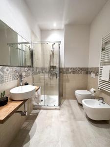 a bathroom with a shower and two sinks and a toilet at A 2 Passi Bed and Breakfast in Faenza