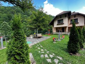 uma casa com um quintal com árvores e um parque infantil em Вила 11 - семейна почивка в сърцето на Балкана em Ribarica