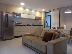a living room with a couch and a kitchen at Maravilhoso Apartamento Reserva DNA Ubatuba in Ubatuba